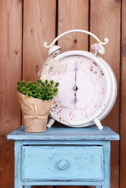 Interior design with big alarm clock and plant on tabletop on wooden planks background — Stock Photo, Image