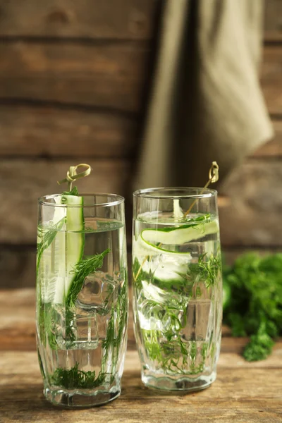Glazen met verse biologische komkommer water op houten tafel — Stockfoto