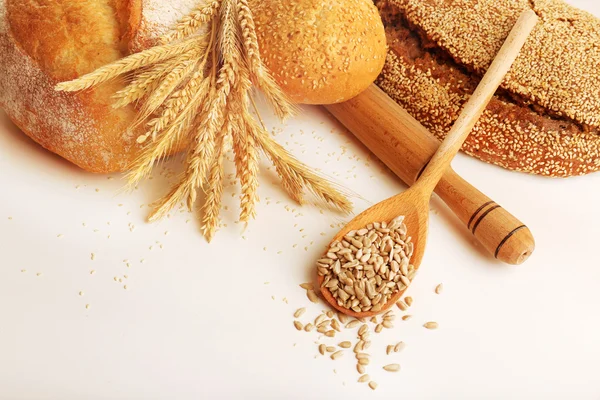 Pane fresco con grano e cucchiaio di semi di girasole isolati su bianco — Foto Stock