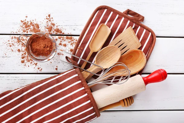 Set of kitchen utensils with cocoa in mitten on wooden background — Stock Photo, Image