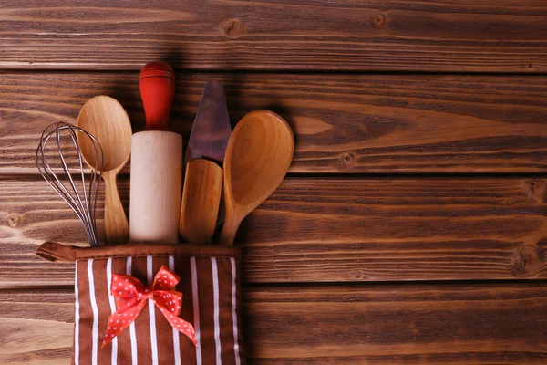 Set of kitchen utensils in mitten on wooden planks background — Stock Photo, Image