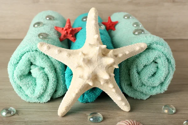 Beautiful towels with sea stars and decorative stones on wooden background — Stock Photo, Image