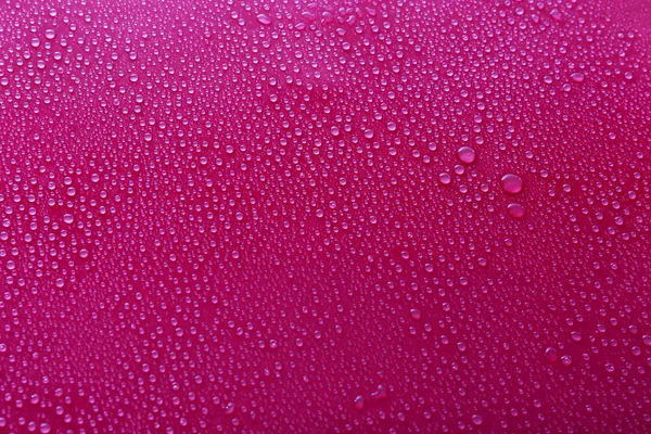 Water druppels op glas op roze achtergrond — Stockfoto