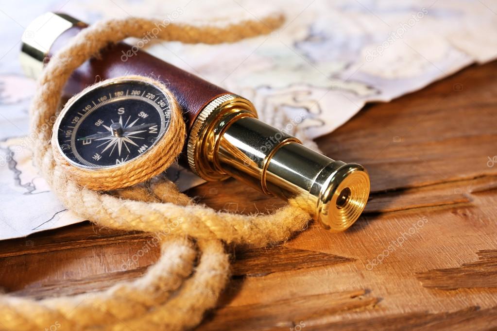 Marine still life spyglass, compass, rope and world map on wooden background