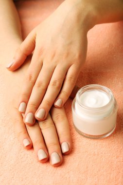 Kumaş arka plan üzerinde krema kavanozu ile eller