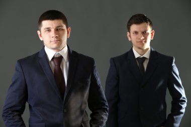 Gri arka plan üzerinde iki yakışıklı iş adamları