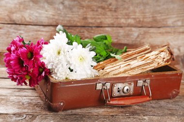 Eski kitaplar ve çiçeklerle ahşap arka plan üzerinde eski tahta bavul