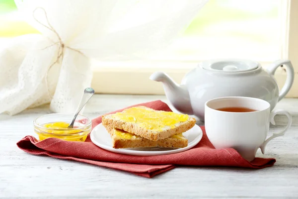 Toasts with honey on plate and cup of tea on light background — Stock Photo, Image