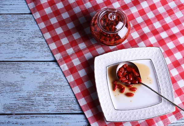 Mermelada de bayas de Goji en cuchara en plato con frasco en la mesa de cerca — Foto de Stock