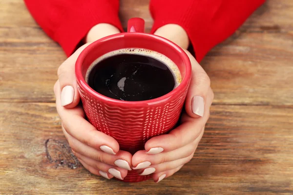 Mains féminines tenant une tasse de café sur fond en bois — Photo