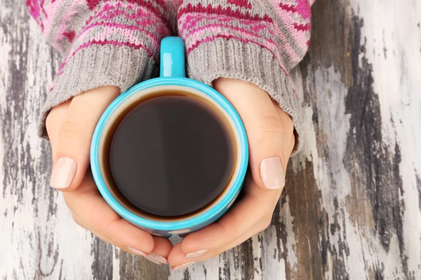 Female hands holding cup of coffee on wooden background — Stock Photo, Image