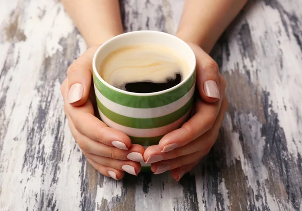 木製の背景にコーヒーのカップを保持している女性の手 — ストック写真