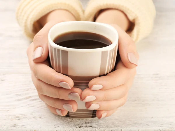 Mains féminines tenant une tasse de café sur fond en bois — Photo