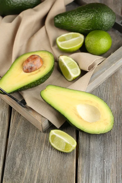 Aguacate con limas en bandeja sobre fondo de madera — Foto de Stock