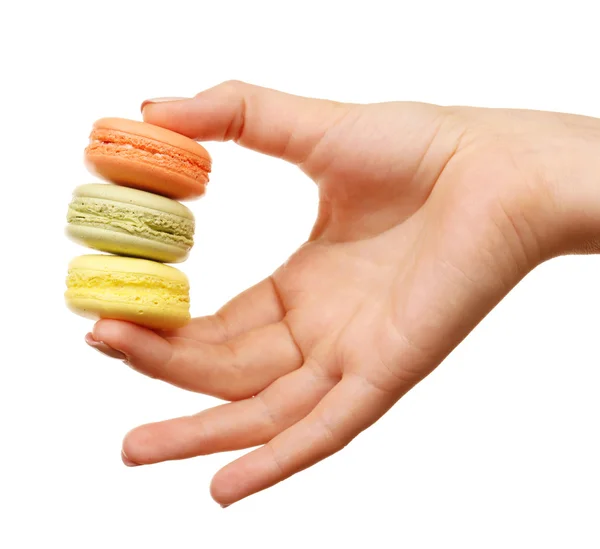 Läckra färgglada macaroons i kvinnlig hand isolerad på vit — Stockfoto
