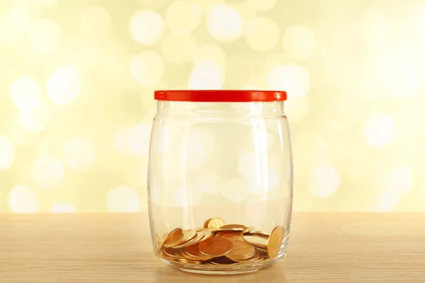 Monedas de oro en botella de vidrio sobre fondo brillante —  Fotos de Stock