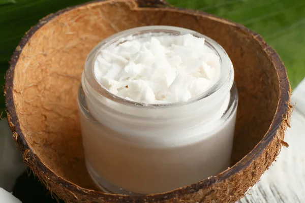 Aceite de coco fresco en botella de vidrio y hoja verde sobre fondo de mesa de madera — Foto de Stock