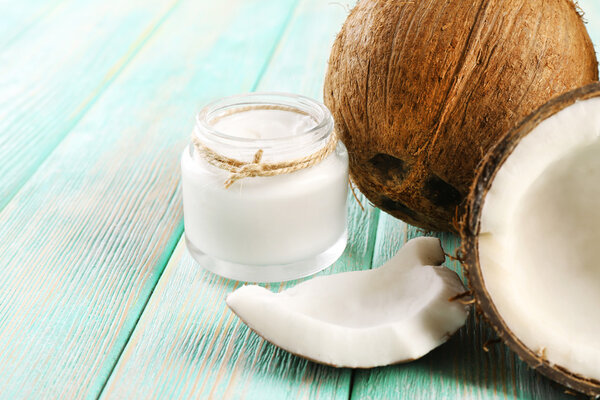 Fresh coconut oil in glassware on color wooden table background