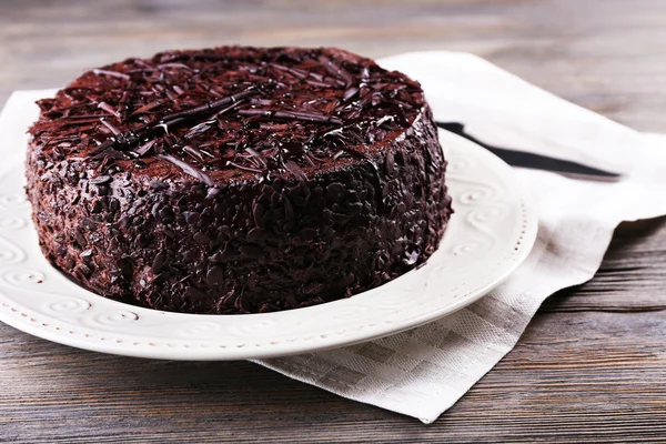 Вкусный шоколадный торт на тарелке с салфеткой на деревянном столе — стоковое фото