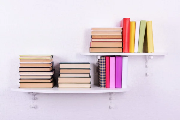 Bücher auf Regalen auf weißem Wandhintergrund — Stockfoto