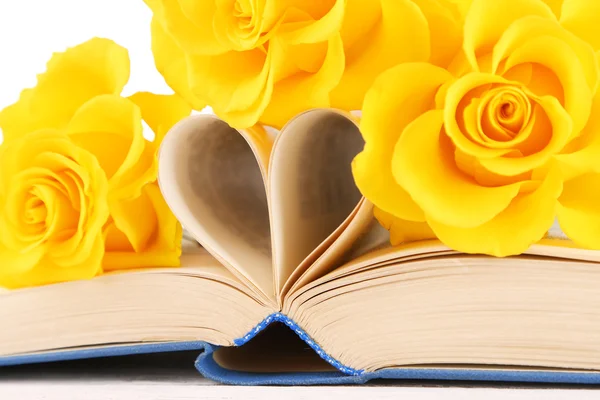 Open book with shape of heart from pages and yellow roses, closeup — Stock Photo, Image