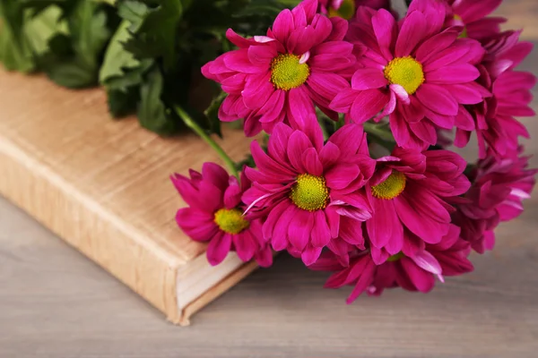 Lindas flores com livro sobre mesa de madeira, close-up — Fotografia de Stock