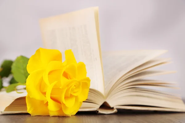 Libro con rosa amarilla sobre mesa de madera sobre fondo claro — Foto de Stock