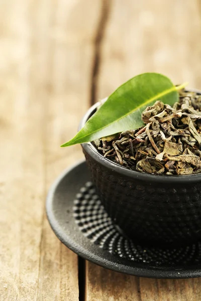 Zielona herbata z liści w Pucharze na starym drewnianym stole — Zdjęcie stockowe