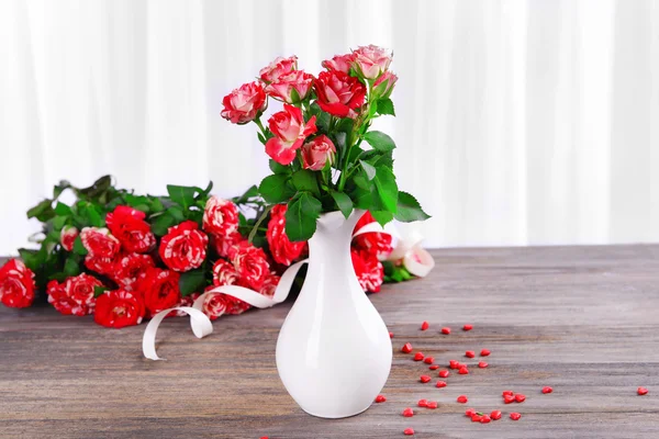 Krásná růže ve váze na stole na světlé pozadí — Stock fotografie