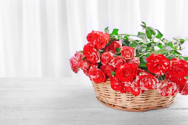 Hermosas rosas en canasta de mimbre en la mesa sobre fondo claro —  Fotos de Stock