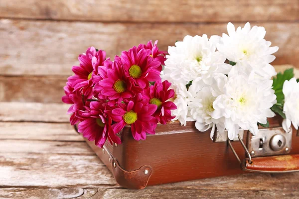 Old wooden suitcase and flowers on wooden background — Stock Photo, Image