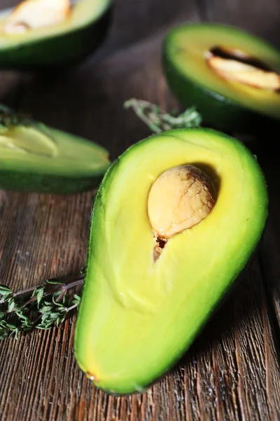 Sliced avocado with herb on wooden background — Stock Photo, Image