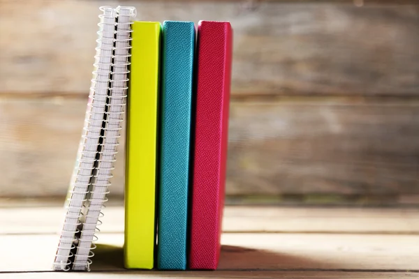 Cadernos coloridos e caneta na velha mesa de madeira — Fotografia de Stock