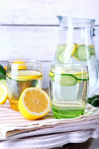 Agua dulce con limón y pepino en cristalería sobre fondo de madera —  Fotos de Stock