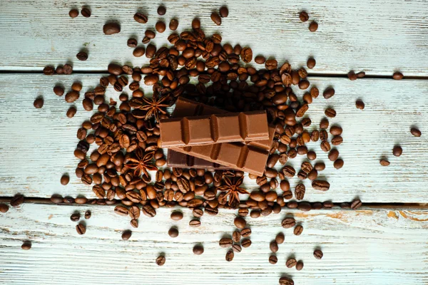 Yıldız anason ve ahşap zemin üzerine kahve çekirdekleri ile çikolata — Stok fotoğraf