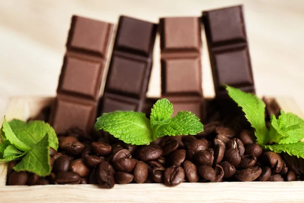 Still life with set of chocolate in wooden box of coffee grains, closeup — Stock Photo, Image