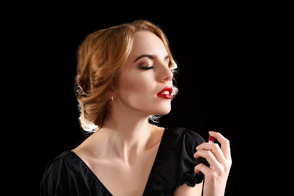 黒い背景に香水瓶と美しい若い女性 — ストック写真