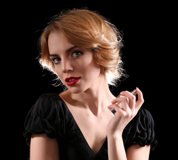 Hermosa joven con botella de perfume sobre fondo negro —  Fotos de Stock