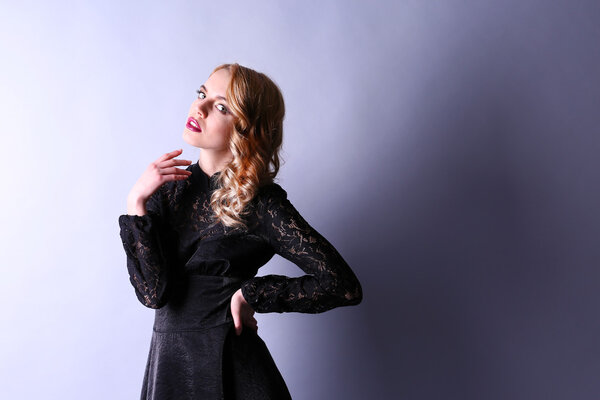 Portrait of young woman in black dress on light background