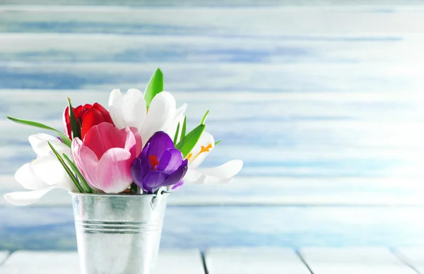 Hermosas flores de primavera en cubo de metal sobre fondo de color — Foto de Stock