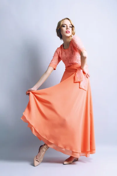 Beautiful young woman in color dress posing on light background — Stock Photo, Image