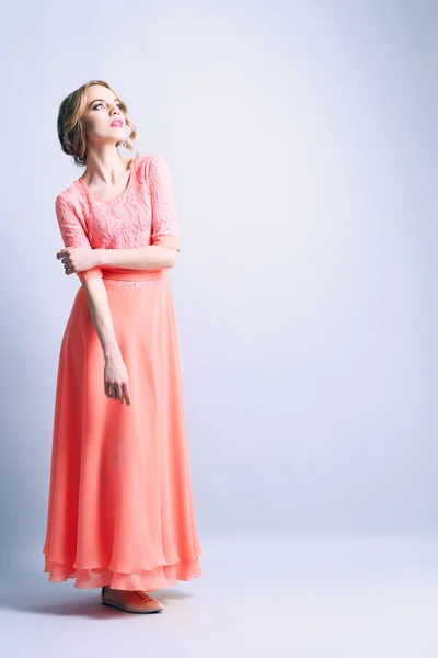 Schöne junge Frau in farbigem Kleid posiert auf hellem Hintergrund — Stockfoto