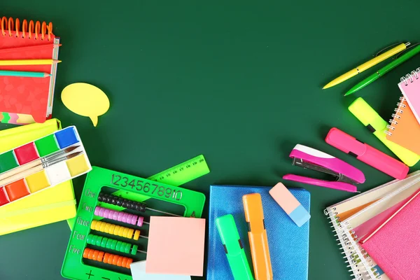 Bright school supplies on blackboard background — Stock Photo, Image