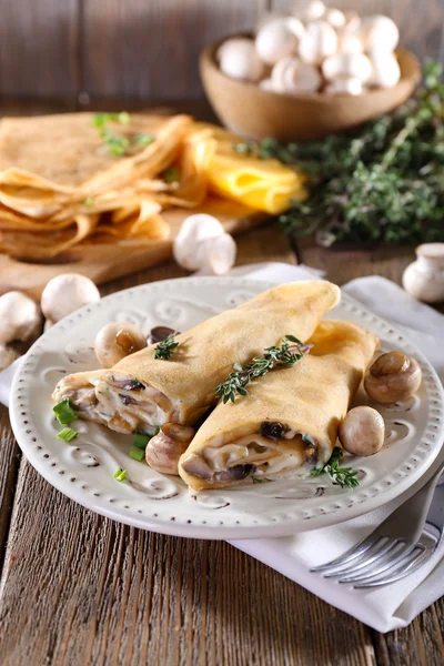 Pfannkuchen mit cremigen Pilzen im Teller auf Holzgrund — Stockfoto