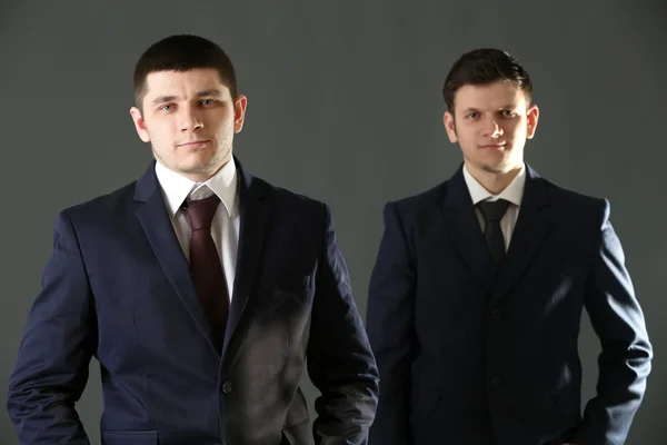 Two handsome businessmen on gray background Stock Photo