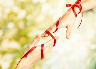 Man's and woman's hands tied with ribbon on sunny nature background clipart