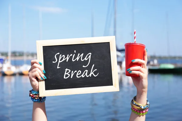 Spring break concept. Chalkboard in female hands on beach background — Stock Photo, Image