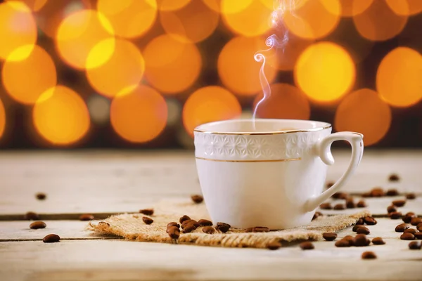 Cup of coffee on wooden table on bright background — Stock Photo, Image