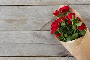 Kağıt ahşap masa arka plan üzerinde kırmızı gül sarılı