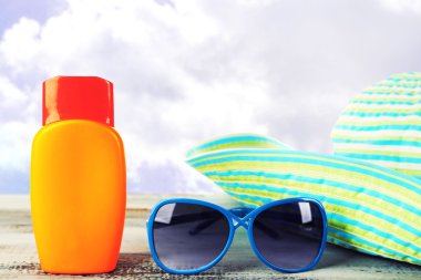 Güneş güneş gözlüğü ve şapka üzerinde beyaz izole tablo ile krem şişe